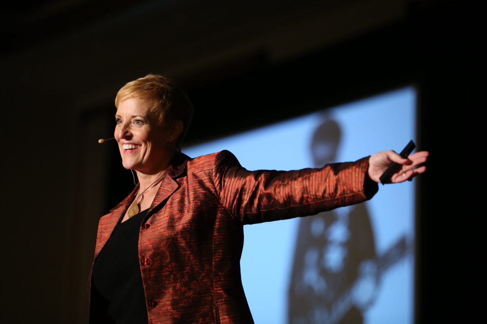 A woman in red jacket pointing to a projector screen.