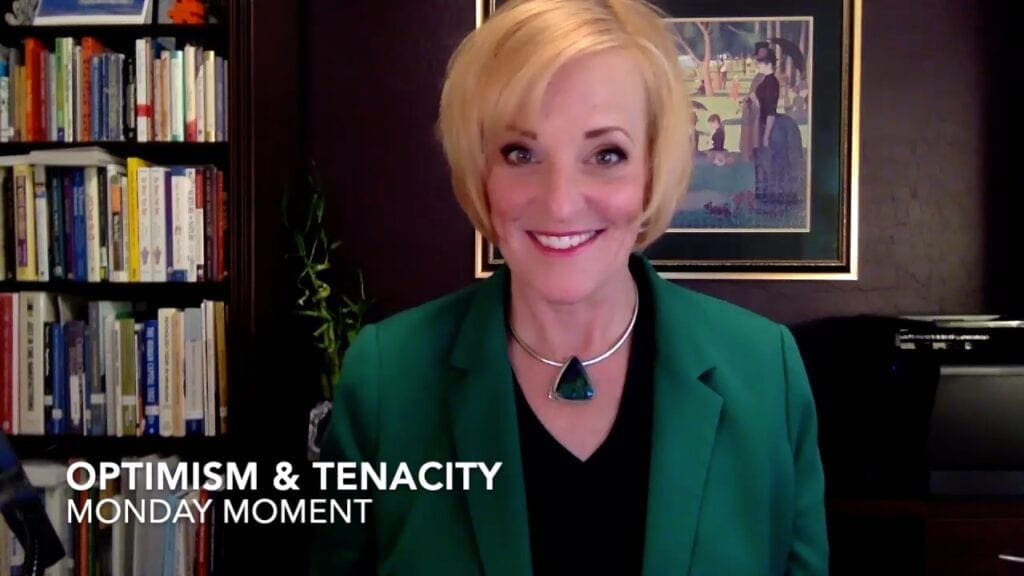 A woman in green jacket and black necklace.