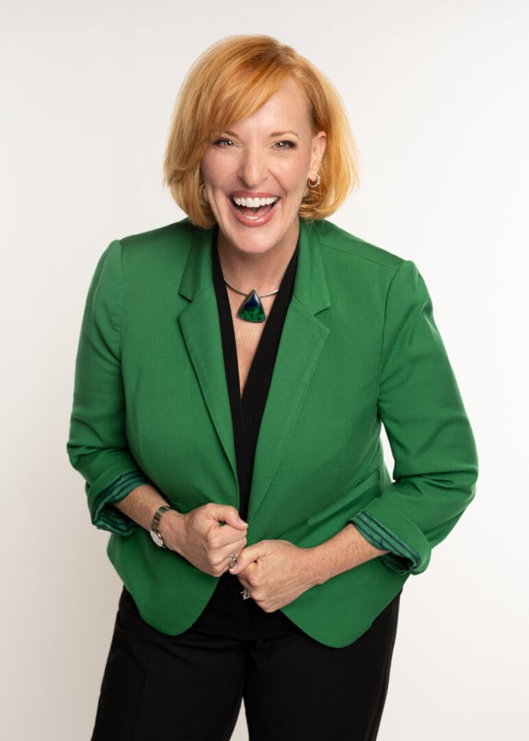 A woman in green jacket smiling for the camera.